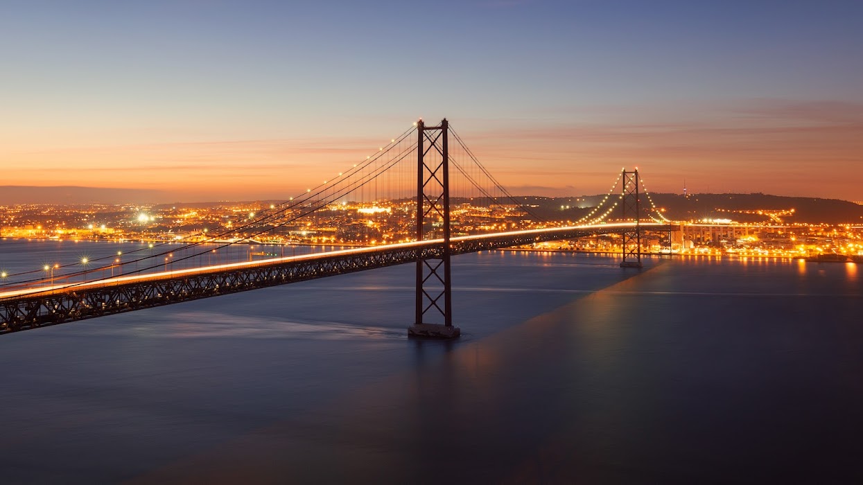 Ponte 25 de Abril e Lisboa vistas desde a margem sul durante a noite.